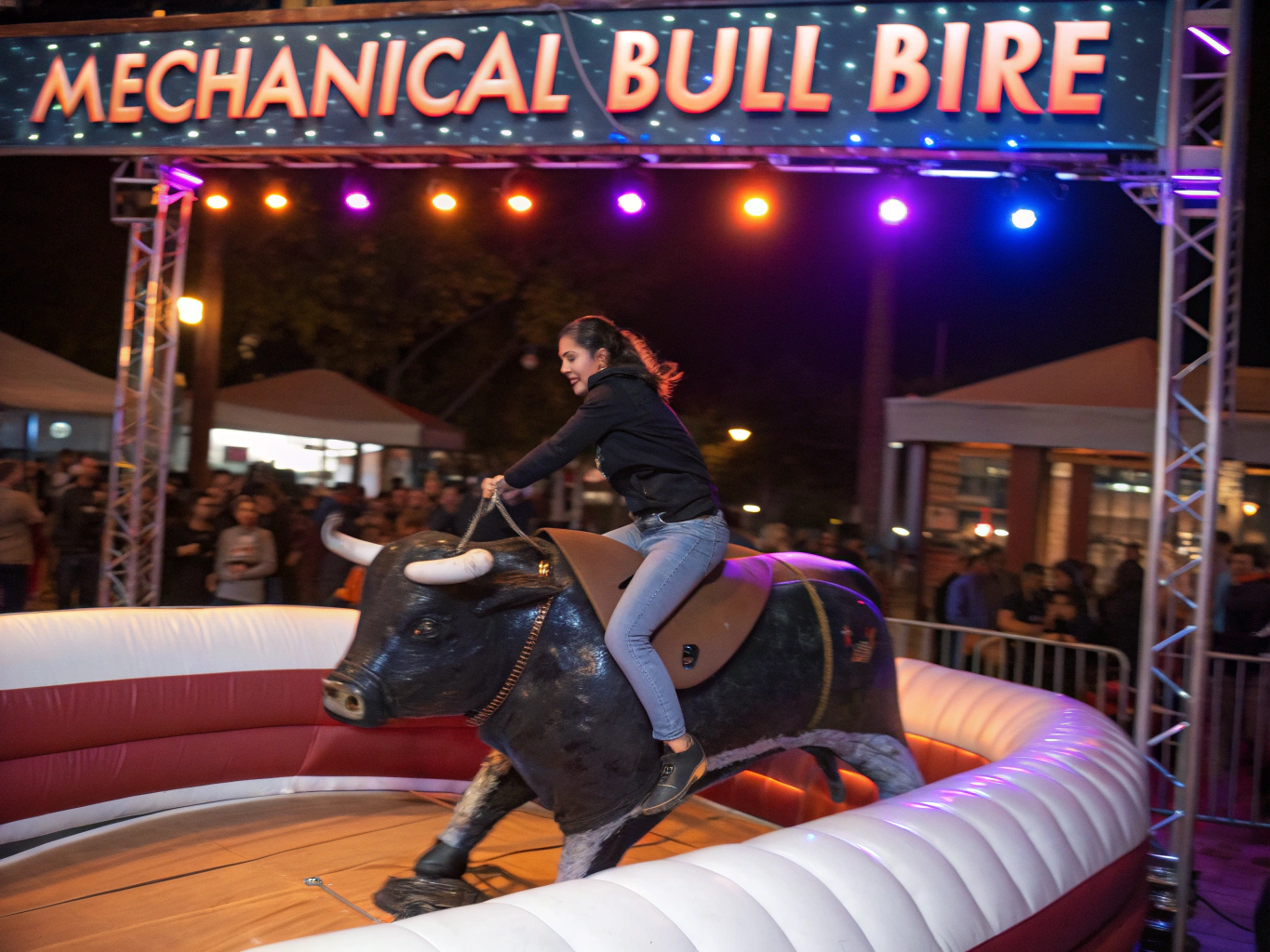 Powered mechanical bull riding machine inside full inflatable safety arena with operator console